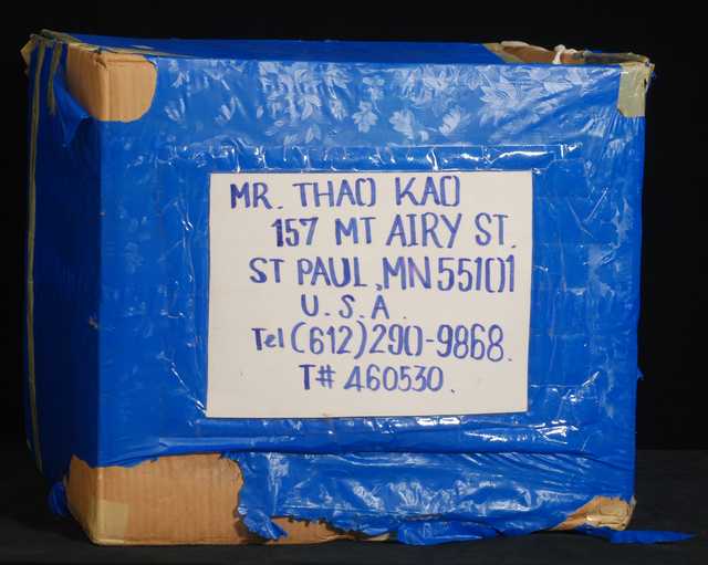 Color image of a corrugated cardboard box used as a packing carton by Blia Cha Thao and family—Hmong refugees who moved from Thailand to Minnesota in 1993.