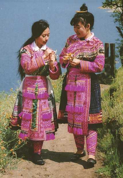 Color scan of a Hmong New Year postcard showing two young women in traditional Hmong dress, c.1980s.