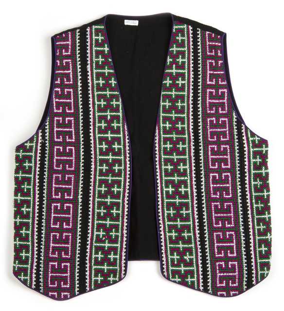 Color image of a reversible cotton vest with front panels of geometric cross-stitching made by a Minnesotan Hmong woman and sold by the Southeast Asian Ministry. Worn by Bea Vue-Benson, c.1999.
