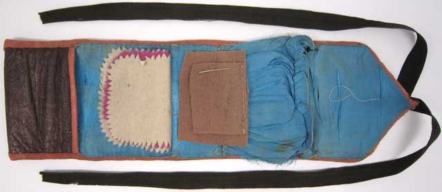 A "soldier's housewife" sewing kit made from a strip of leather with a twill-like finish and lined with silk.