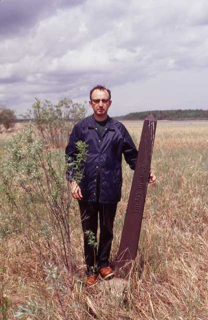 Color photograph of a Northwest angle marker and author William E. Lass provides a sense of the marker's scale, 1972.