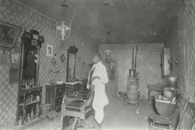 Black and white photograph of African American barber Prince Honeycutt in his Fergus Falls shop, c.1900.