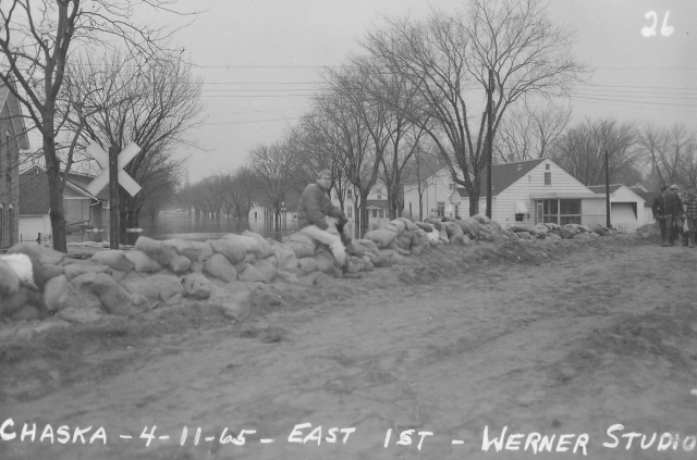 Black and white photograph of water surrounding new courthouse. Flood waters of 1965, Chaska