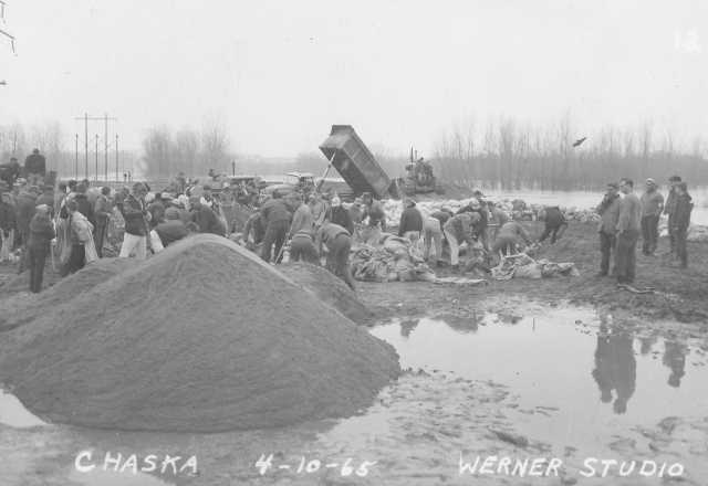 Black and white photograph of the rebuilding dikes in Chaska during flood of 1965. Photographed by Werner Studio, April 10, 1965.