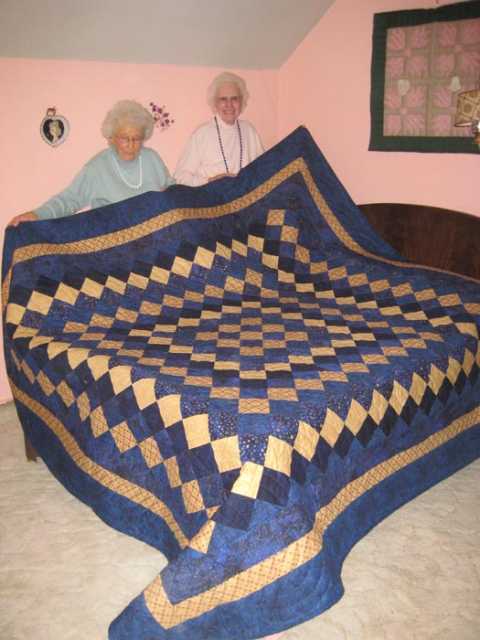 Color image of Anna and Lena Ewert posing with a quilt they made and donated to the Tabor College Carson Center quilt auction, 2009.