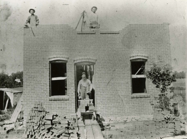 Black and white photograph of a brick house under construction in Meire Grove c.1890.