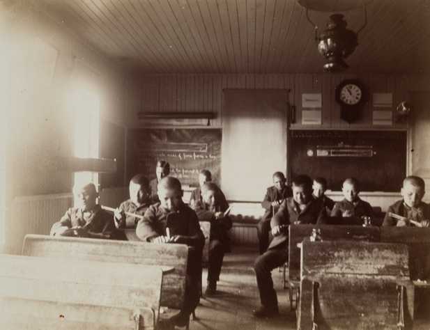 Black and white photograph of students inside a classroom at a Native American boarding school, c.1900.