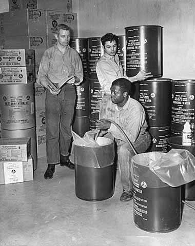 Black and white photograph of people stocking fallout shelter at St. Casimir’s School, St. Paul, 1962.