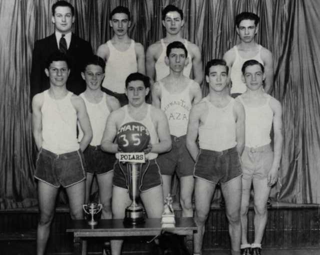 Black and white photograph of a young men's basketball team at the Jewish Educational Center in Saint Paul, c.1940. The programming arm of the J. E. C., known as the Jewish Center Activities Association, oversaw social and recreational activities at the Center.