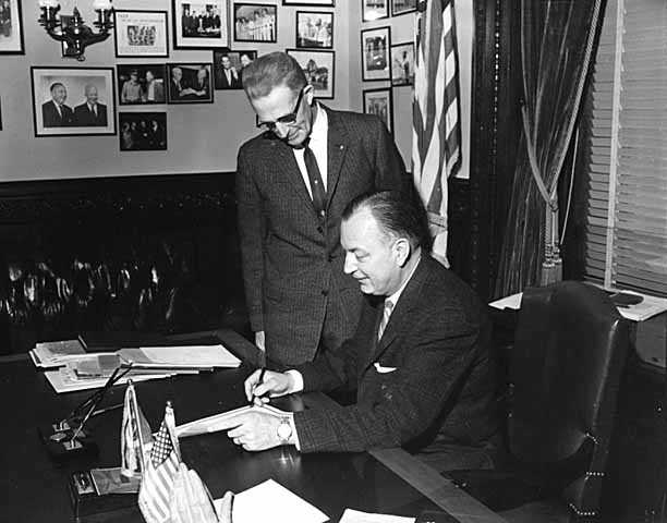 Black and white photograph of Governor Elmer Benson signing a bill with Grange Master William B. Pearson looking on, 1963. Photographed by Eugene Debs Becker. 