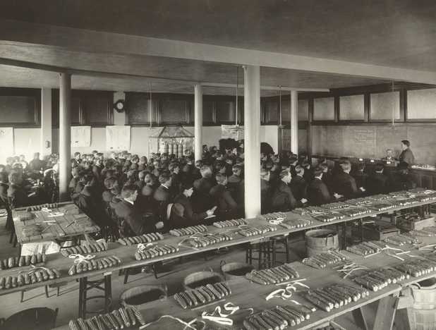 Black and white photograph of a class in corn judging, University of Minnesota, College of Agriculture, St. Paul, ca. 1910.
