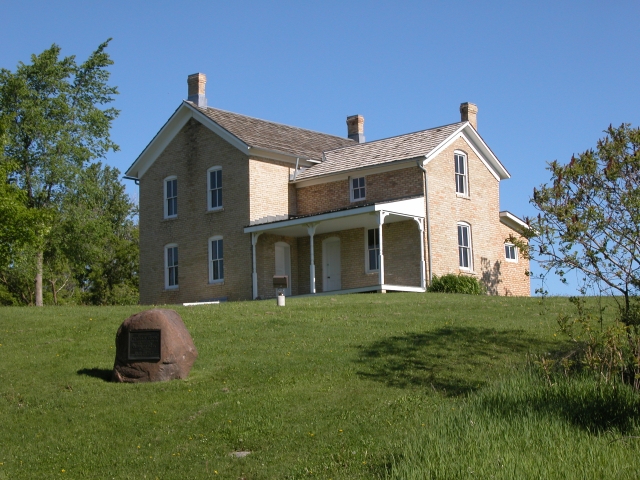 Image depicting the 1876 Chaska brick Wendelin and Julianna Grimm house, showing 1924 Grimm alfalfa marker in foreground, 2004.