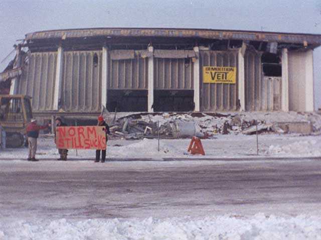 Demolition of the Met Center (Metropolitan Sports Center) in Bloomington, 1994. The stadium was demolished after the North Stars hockey team left Minnesota. A common refrain among North Stars fans, who blamed owner Norm Green for abandoning the state, was “Norm sucks.”  