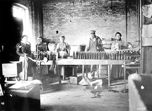 Black and white photograph of M. A. Gedney Company workers bottling product, c.1912.