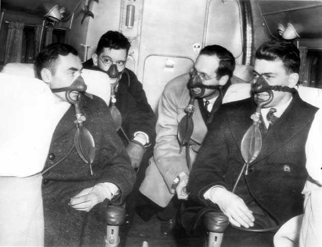 Black and white photograph of passengers with oxygen masks on Northwest Airlines plane, c.1940.