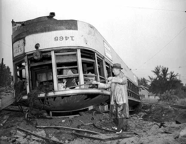 Black and white photograph of Minneapolis farewell to streetcars. TCRT Chairman, Fred A. Ossanna, smashes the window of an electric streetcar following the implementation of motor buses in Minneapolis, 1954.