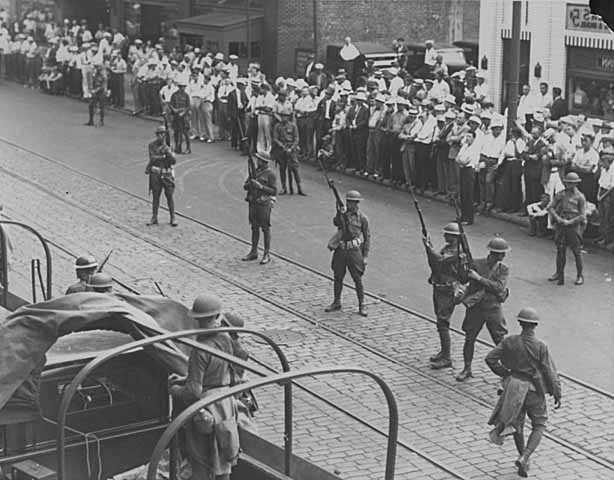 Black and white photograph of National Guard troops keeping a crowd back during a raid on strike headquarters in Minneapolis, 1934.