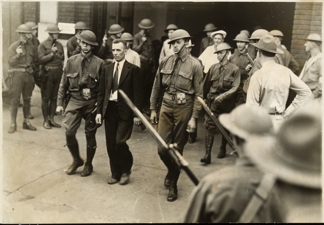 Black and white photograph of Vincent R. Dunne, strike committee member, arrested and held at the provost guard stockade at the State Fair grounds, 1934. 