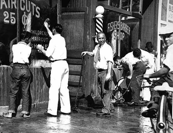 Black and white photograph of the exterior of Fisher’s Barber Shop splashed with red paint, c.1940s.