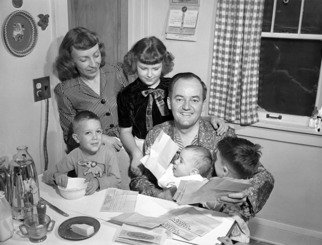 Black and white photograph of Hubert H. Humphrey reading from a pile of telegrams the day after winning a seat in the U.S. Senate, November 3, 1948.