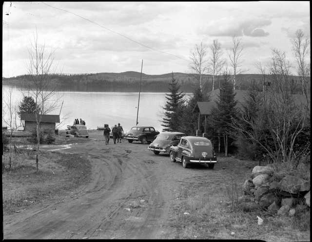 A view of cars, visitors, and Gunflint Lake at Gunflint Lodge. Photograph by Kenneth Melvin Wright, ca. 1950.