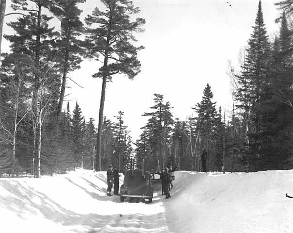 People standing around a car on the Gunflint Trail during winter. Photograph by Kenneth Melvin Wright, ca. 1944.