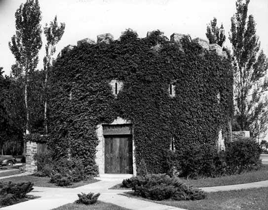 Black and white photograph of the he Round Tower covered in vegetation, c.1942. Photographed by Norton and Peel.