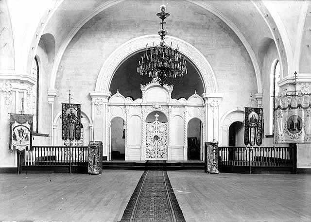 Black and white photograph of the interior of the sanctuary in St. Mary’s Orthodox Cathedral, Minneapolis with an icon screen and banners, c.1906. 