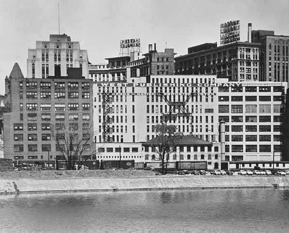 Black and white photograph of the West Publishing complex seen from the Mississippi River, 1955. 
