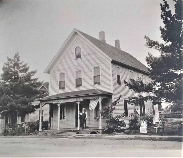 Three unidentified people in front of the Nerstrand Hotel with American flags on display, ca. 1890. Nerstrand city records, Nerstrand City Hall.