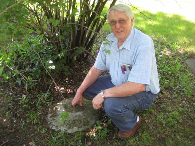 Color image of Norman Ewert, ca. 2013, with a disk blade he made as a temporary tombstone for the grave of Anna Funk Wiens inside Carson Mennonite Brethren Church Cemetery.