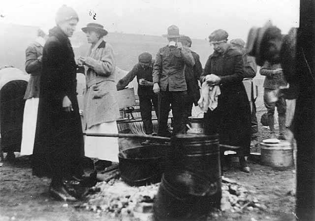 Black and white photograph of Red Cross workers serving meals to National Guard and survivors, Moose Lake forest fire, 1918.