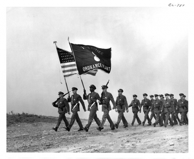 Soldiers marching with Twin Cities Ordnance Plant flag