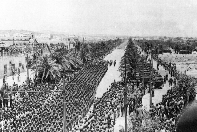 Black and white photograph of U.S. Soldiers of the Thirty-fourth Division marching through Tunis, 1943.