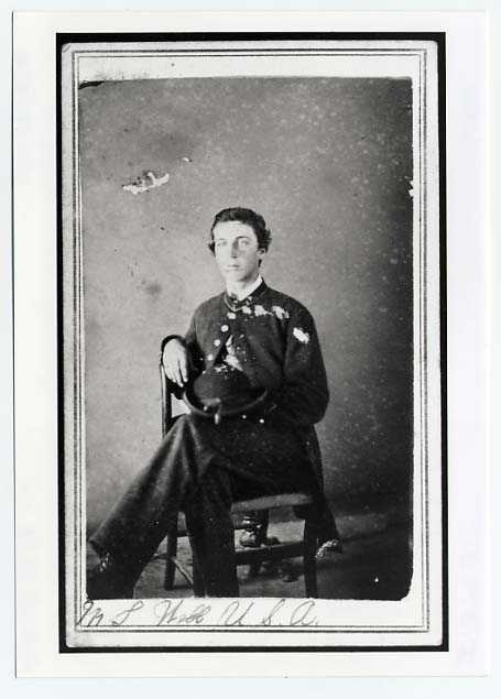 Photograph portrait of Martin Webb. He is seated in a chair with his legs crossed and he is wearing his uniform.