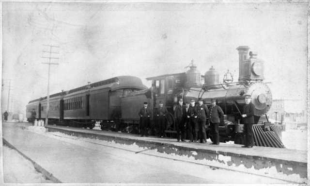 St. Paul and Duluth Railroad Company train and several railroad men, including John Wesley. Blair was an African American porter on the Eastern Minnesota train that rescued hundreds of people from the fire in Hinckley. He was honored as one of the heroes. He is second from the right in the photograph. 