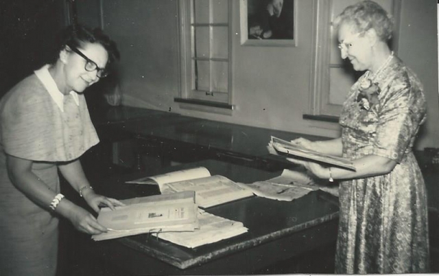 Black and white photograph of Eunice Morberg and Mae Rideout looking at Crookston BPW scrapbooks, 1959.