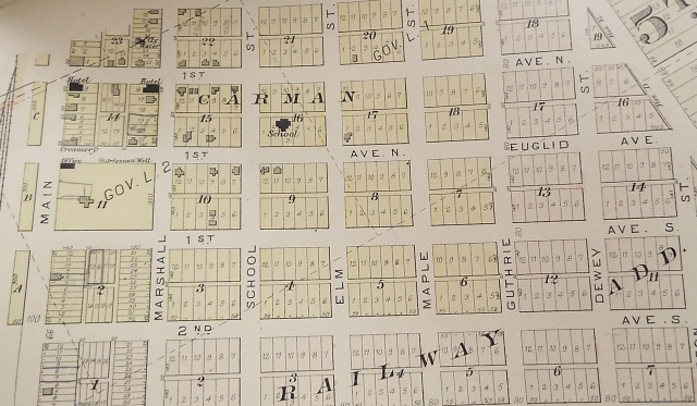 Photograph of a page in a Polk County plat book (1902) showing Carman’s street layout, including a creamery, hotels, a school, and artesian wells.