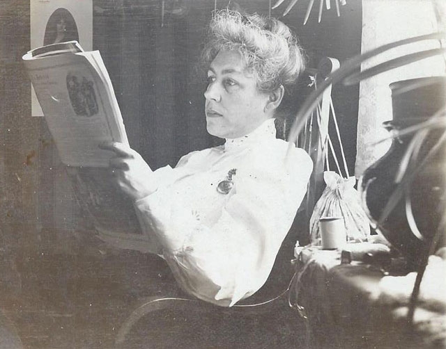 Black and white photograph of Eliza Childs reading a newspaper, ca. 1900–1910.