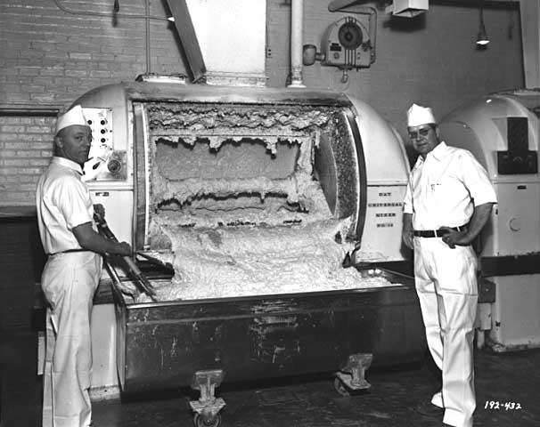 Two men posing next to a Ry-Krisp batter-mixing machine.