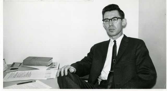 Black-and-white photograph of Professor Roy W. Meyer at his Mankato State College desk in the early 1960s.