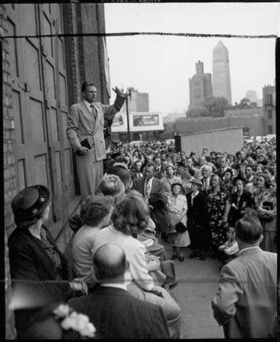 Photograph of the Reverend Billy Graham speaking at the stage door of the Minneapolis Auditorium. 