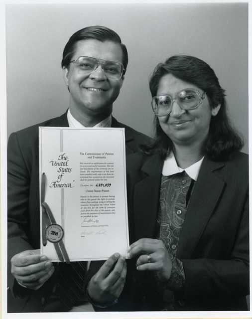 Black and white photograph of Sam (Smarajit) and Sumita Mitra, a husband-and-wife team of 3M research scientists, display their U.S. patent for copolymerizable UV stabilizers, 1987.