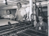 Black and white photograph of staff of the Waconia Patriot at a printing press. Art Wessele is shown in the middle. Date and photographer unknown.