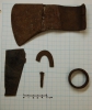 Color image of artifacts metal detected by a relic collector prior to 1972 and identified as an iron ferule, a piece of fire steel, a rosehead nail, a fragment from the bottom of a kettle, and an axe head.