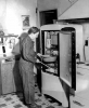 Black and white photograph of Linda Benitt at the refrigerator in her kitchen, Dakota County, 1944.