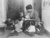 Black and white photograph of a woman reading to children at the Neighborhood House, c.1925.
