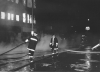Black and white photograph of firefighters battling the flames in the Opera House Block in 1987.