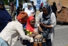 Photograph of a child playing a traditional Somali drum with help from adults