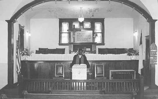 Black and white photograph of Rev. Alphonse Reff standing in the pulpit at St. Mark’s African Methodist Episcopal Church, Duluth, July 8, 1975.